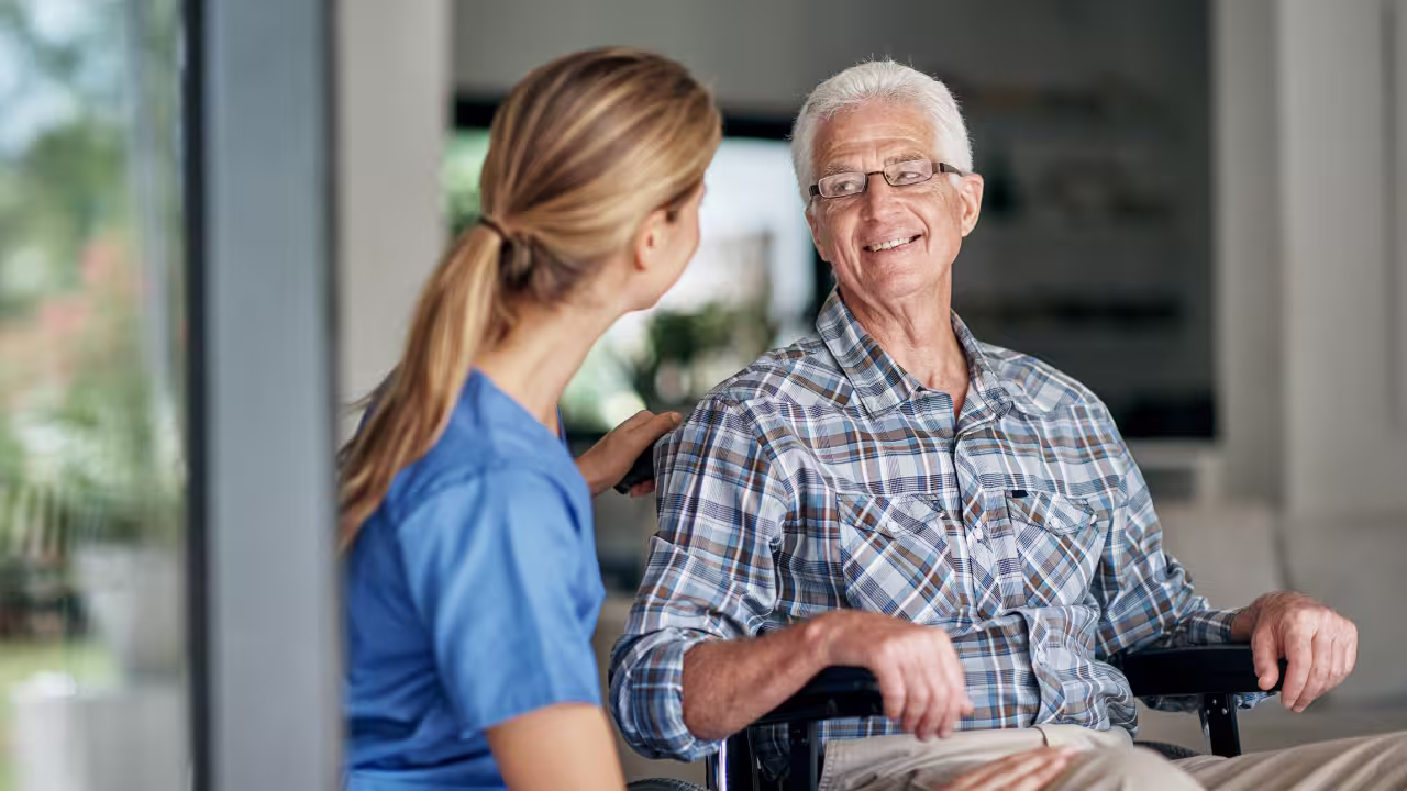 Senior im Gespräch mit einer Betreuungskraft zu Hause